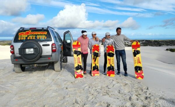 A group of people enjoying sandboarding at WILD X Adventures at The Atlantis Dunes