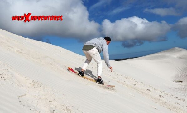 A person enjoying sandboarding at WILD X Adventures at The Atlantis Dunes