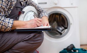 A stock photo of a man servicing a washing machine