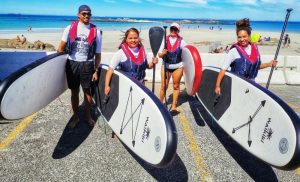 A group of people trying SUPing at Cape Town Surf School in Bloubergstrand