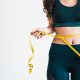 A stock photo of a woman with a tape measure around her waist, after a laser slimming treatment