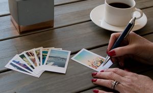 A photo of a woman writing on mini photo prints from Prints-Ta-Go available for nationwide delivery