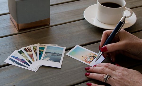 A photo of a woman writing on mini photo prints from Prints-Ta-Go available for nationwide delivery