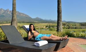 A woman relaxing by the pool at Val du Charron in Bovlei